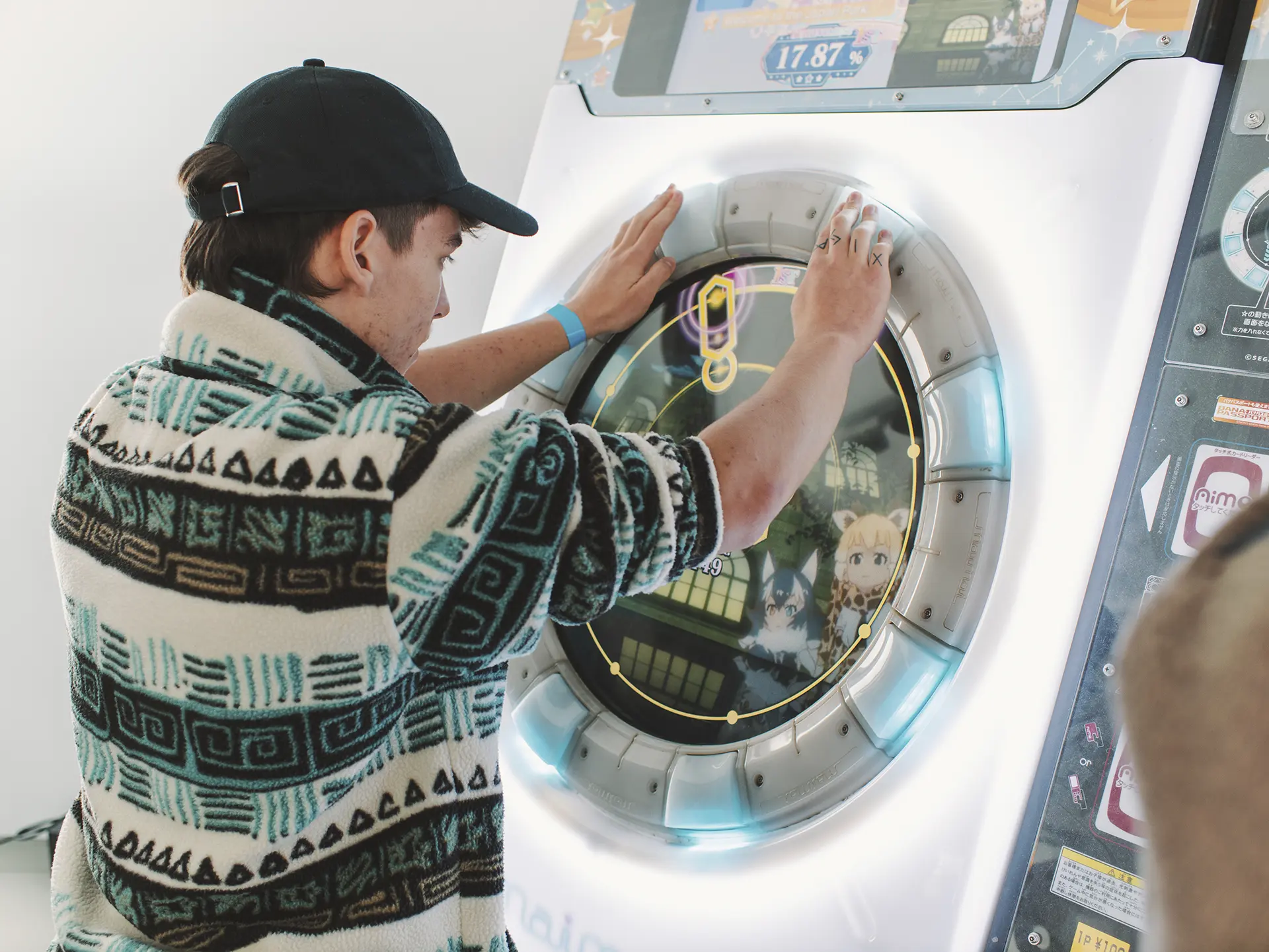 joven con gorra negra jugando a máquyina arcade japonesa tactil